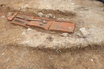 Tombe en bâtière, inhumation en coffrage de tuiles, orientée est-ouest. Des ossements en position secondaire a été retrouvé associé à l’individu en position primaire, à l’extérieur de la bâtière. Datation : fin de l’Antiquité ou début du Moyen Âge.