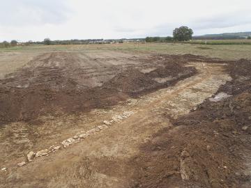 Vue générale de l'aqueduc.  Les dalles de couverture de la canalisation au tracé sinueux manquent par endroits, probablement entraînées par les labours