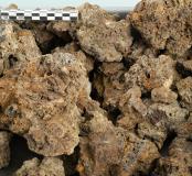 Les déchets créés lors de la production du fer sont multiples. A chaque étape de la production, ces déchets que l'on appelle scories ont une forme particulière. Cette forme permet de déterminer l'étape dans la production de la réduction du minerai de fer. Les scories de fond de four sont plus sombres. Elles sont des dimensions très variables et toujours fragmentaires. Leur surface est couverte de porosités alvéolaires anguleuses et présentent de nombreuses empreintes de charbon.