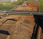 Vue partielle depuis l'ouest des deux zones de fouille, de part et d'autre d'une route. En haut de l'image, le secteur du village ; en bas, l'aire d'ensilage.  Madame, Saint-Gilles le Vieux, Aimargues (Gard), 2013. © Airimage, Inrap